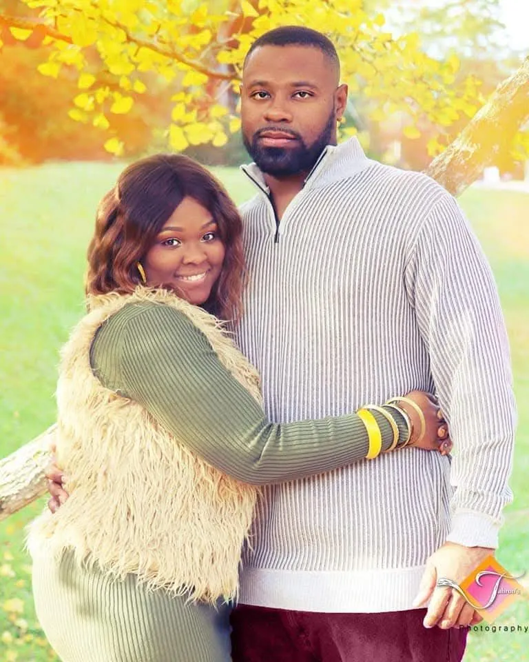 A couple sharing a joyful outdoor portrait beneath autumn trees